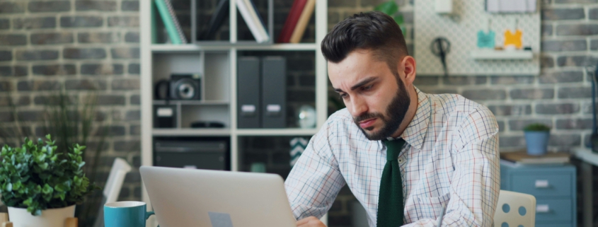 Mann sitzt vor Laptop